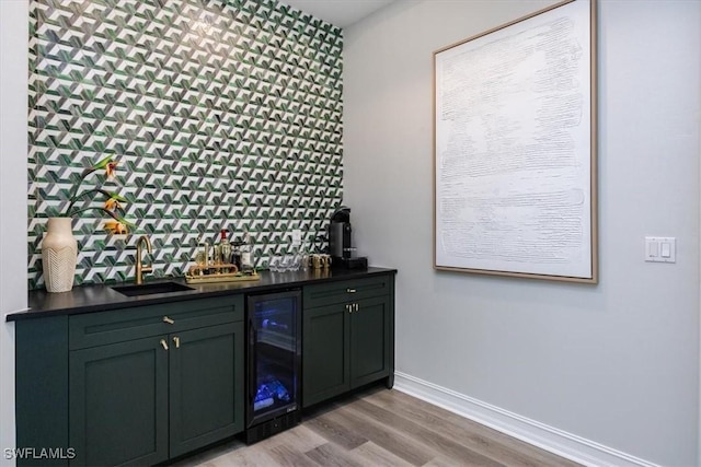 bar featuring sink, light hardwood / wood-style flooring, and beverage cooler