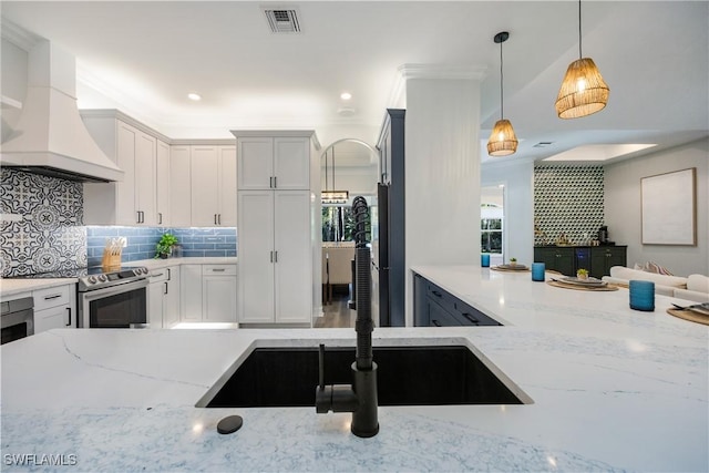 kitchen with decorative light fixtures, white cabinetry, electric stove, light stone counters, and custom range hood