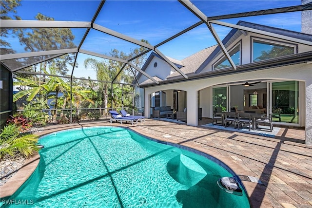 view of swimming pool featuring glass enclosure, ceiling fan, and a patio area