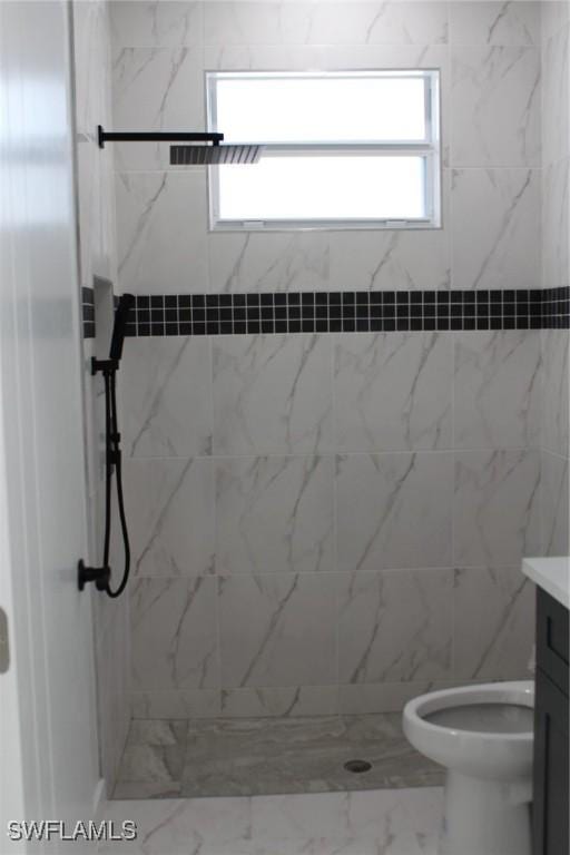 bathroom with a tile shower, vanity, and toilet