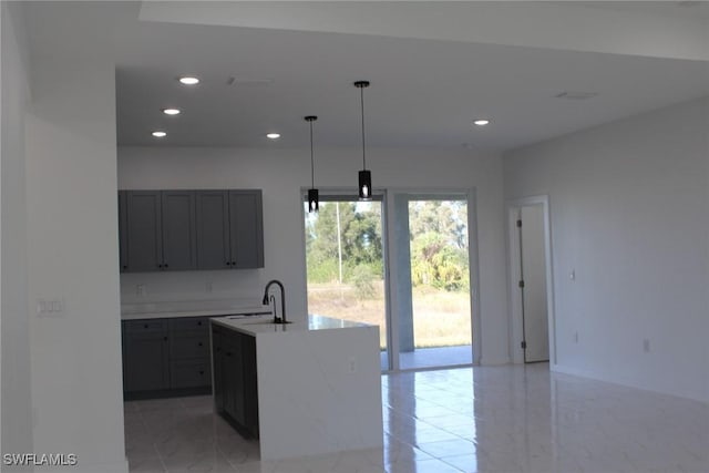 kitchen featuring a center island with sink, hanging light fixtures, gray cabinetry, and sink