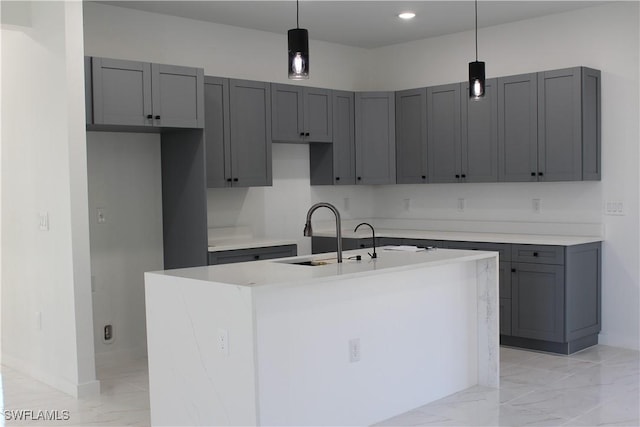 kitchen with a center island with sink, decorative light fixtures, gray cabinetry, and sink