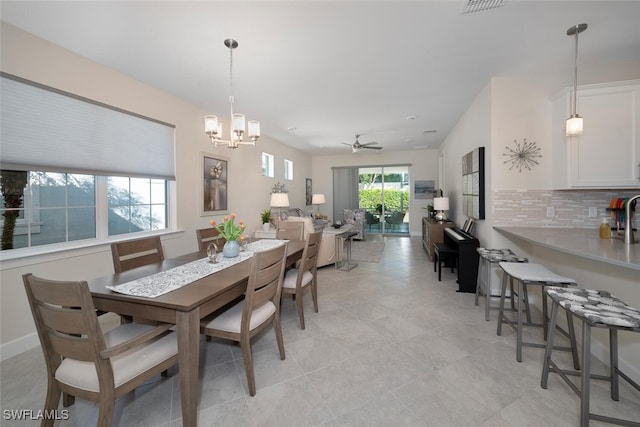 tiled dining area featuring ceiling fan with notable chandelier