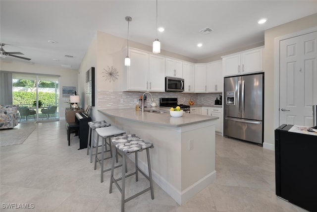 kitchen featuring kitchen peninsula, decorative backsplash, stainless steel appliances, white cabinetry, and hanging light fixtures