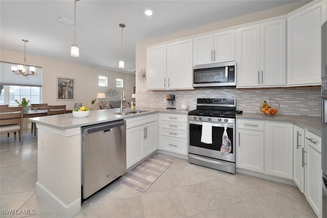 kitchen with sink, hanging light fixtures, appliances with stainless steel finishes, white cabinetry, and kitchen peninsula