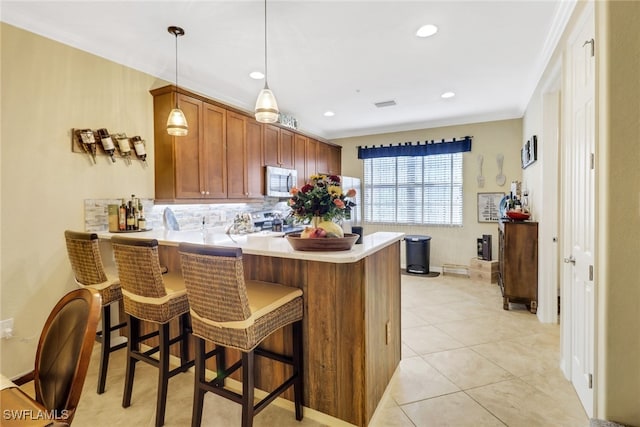 kitchen with stainless steel electric stove, hanging light fixtures, light tile patterned flooring, a kitchen bar, and kitchen peninsula