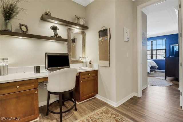 office area with crown molding, light hardwood / wood-style flooring, and built in desk