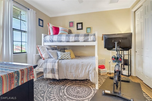 bedroom featuring wood-type flooring, ornamental molding, and a closet