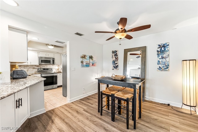 dining space with ceiling fan and light wood-type flooring