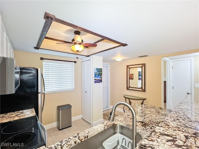 kitchen with stove, light stone counters, ceiling fan, light tile patterned floors, and stainless steel refrigerator