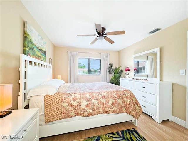 bedroom with ceiling fan, light hardwood / wood-style floors, and multiple windows