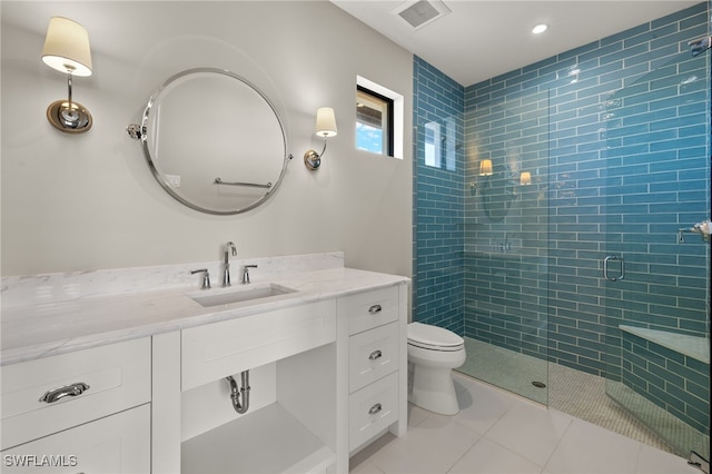 bathroom with a shower with shower door, vanity, tile patterned flooring, and toilet