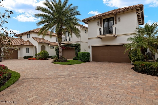 mediterranean / spanish-style home featuring a garage and a balcony