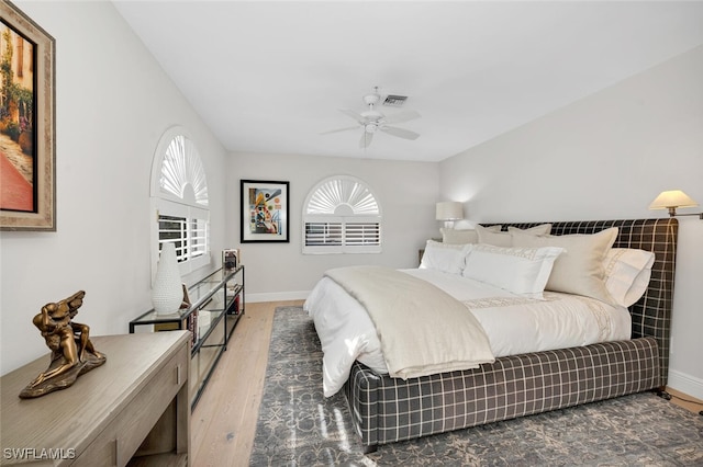 bedroom with ceiling fan, wood finished floors, visible vents, and baseboards