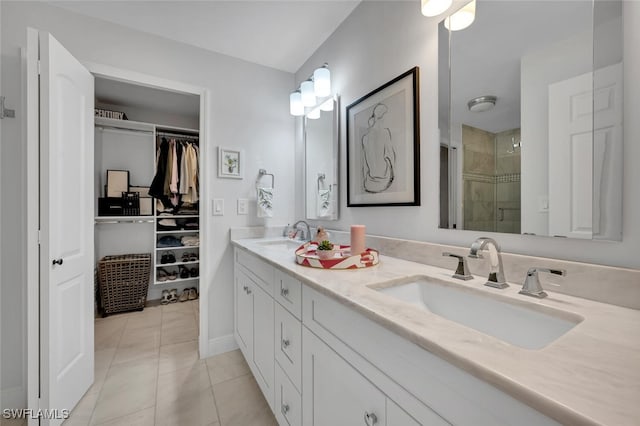 bathroom with tile patterned flooring, a walk in closet, a sink, and a shower stall