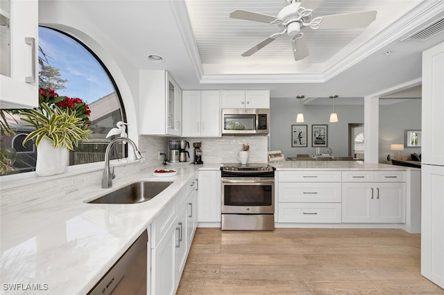 kitchen with pendant lighting, a raised ceiling, sink, white cabinets, and stainless steel appliances