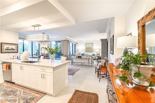 kitchen featuring pendant lighting, sink, light tile patterned floors, dishwasher, and white cabinets