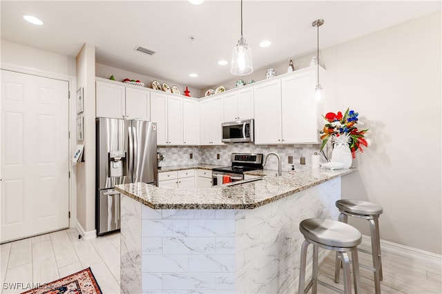 kitchen with pendant lighting, kitchen peninsula, white cabinetry, light stone countertops, and stainless steel appliances