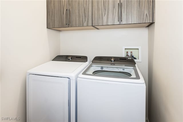 clothes washing area featuring cabinets and separate washer and dryer