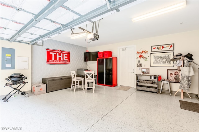 garage with a garage door opener, electric panel, and black refrigerator