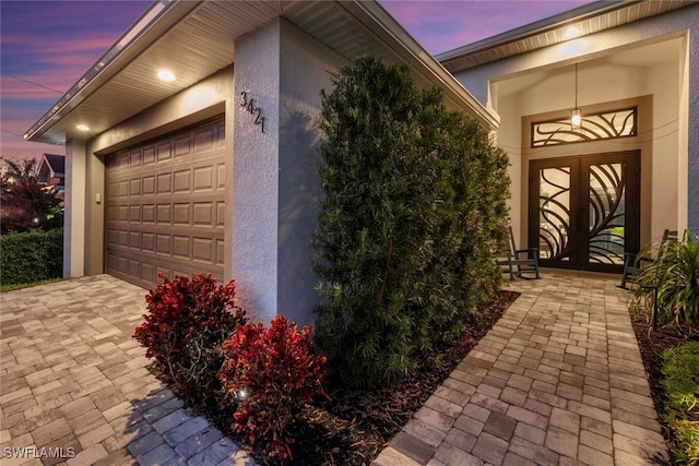 property exterior at dusk with french doors and a garage