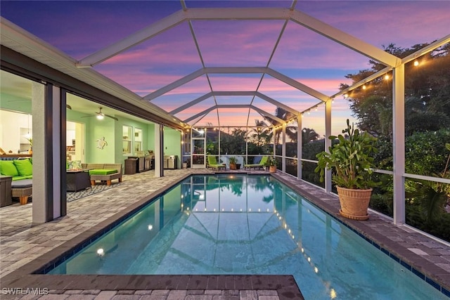 pool at dusk featuring a lanai, an outdoor living space, and a patio