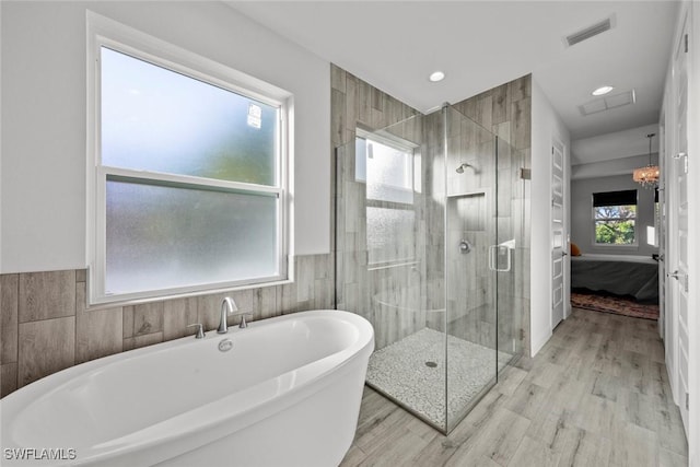 bathroom with plus walk in shower, hardwood / wood-style floors, and tile walls