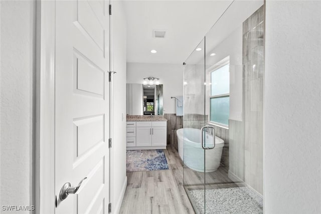 bathroom featuring hardwood / wood-style floors, vanity, tile walls, and shower with separate bathtub