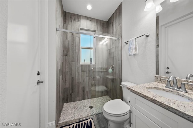 bathroom with vanity, a shower with shower door, and toilet