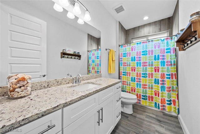 bathroom with a shower with shower curtain, wood-type flooring, vanity, and toilet