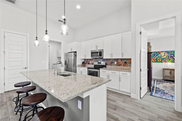 kitchen with white cabinets, pendant lighting, and stainless steel appliances