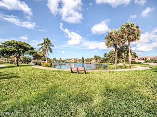 surrounding community with a water view and a lawn