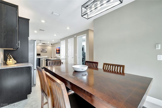 dining area with ceiling fan, light tile patterned floors, and stacked washer / drying machine