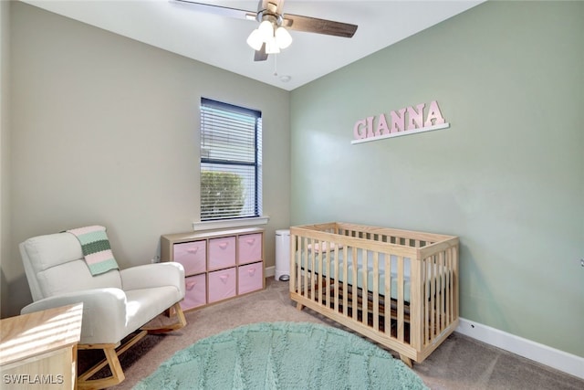 carpeted bedroom featuring a crib and ceiling fan