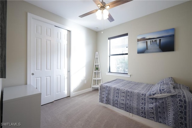 bedroom with ceiling fan, a closet, and light carpet