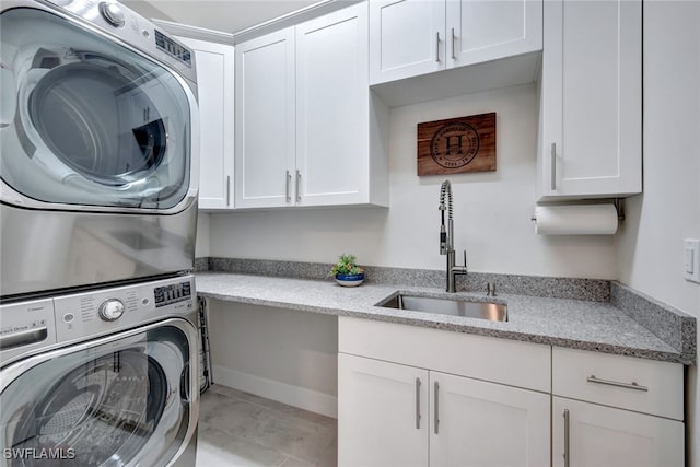 clothes washing area featuring cabinets, light tile patterned flooring, sink, and stacked washer and dryer