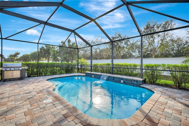 view of swimming pool featuring pool water feature, a water view, glass enclosure, a patio, and a grill