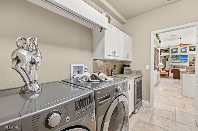 washroom featuring wine cooler, sink, cabinets, and independent washer and dryer