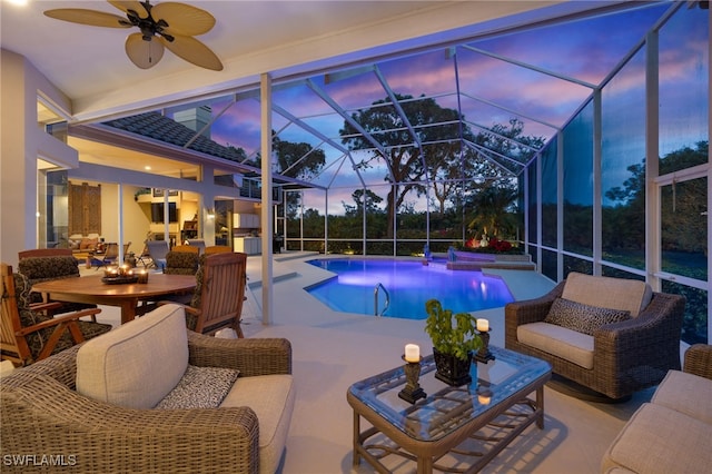 view of pool featuring an outdoor living space, a patio, glass enclosure, and ceiling fan