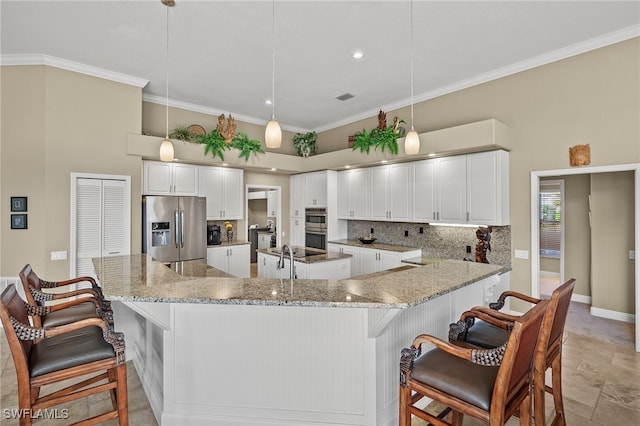 kitchen featuring a kitchen bar, light stone countertops, stainless steel appliances, decorative light fixtures, and white cabinets