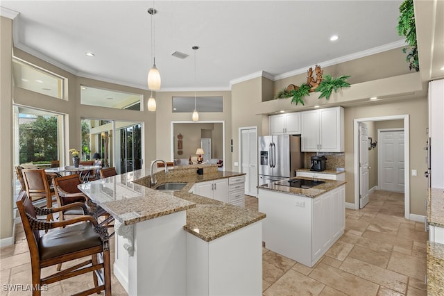 kitchen featuring sink, decorative light fixtures, a large island, light stone counters, and stainless steel fridge with ice dispenser