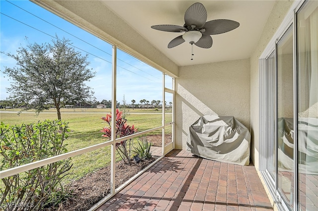 unfurnished sunroom featuring ceiling fan