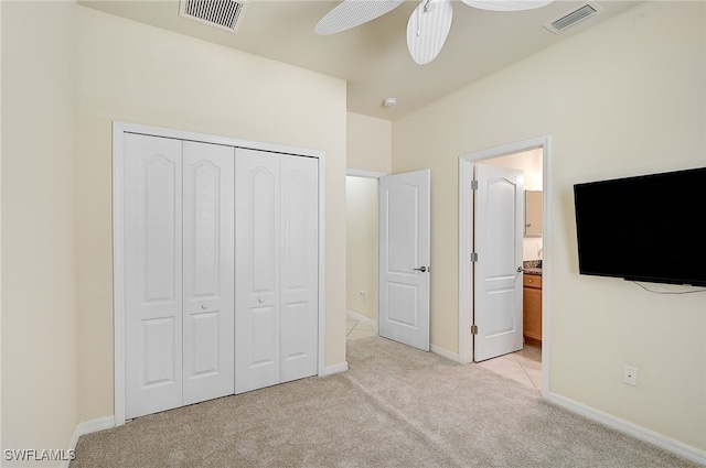 unfurnished bedroom featuring ceiling fan, a closet, ensuite bathroom, and light carpet