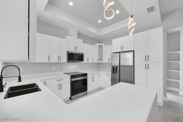 kitchen with pendant lighting, stainless steel appliances, glass insert cabinets, white cabinetry, and a sink