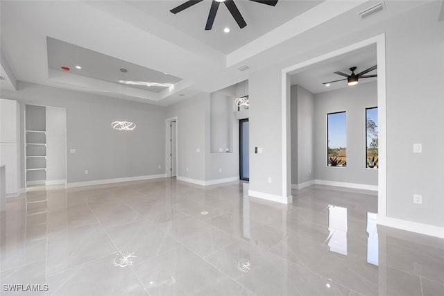 unfurnished room featuring a raised ceiling, visible vents, ceiling fan, and baseboards