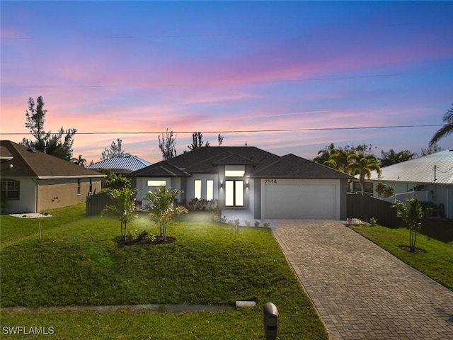 ranch-style home with a front yard, decorative driveway, fence, and an attached garage