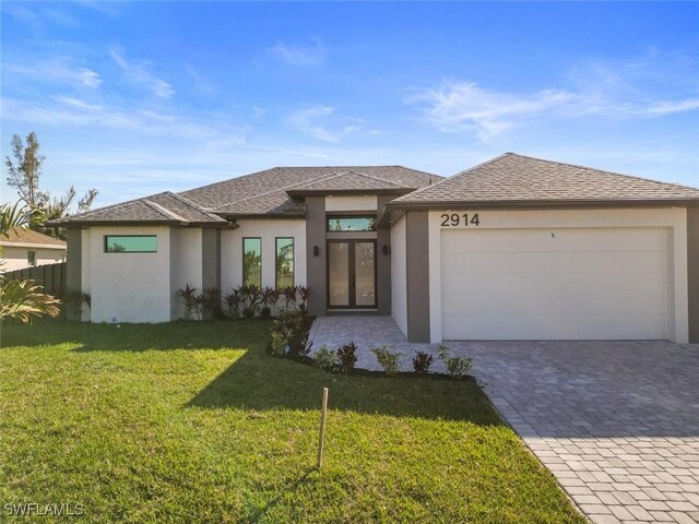 prairie-style house with a garage, decorative driveway, french doors, a front yard, and stucco siding