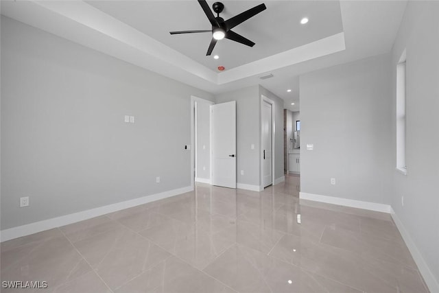 unfurnished bedroom with baseboards, a tray ceiling, and recessed lighting