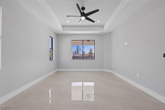 spare room featuring recessed lighting, a raised ceiling, ceiling fan, and baseboards