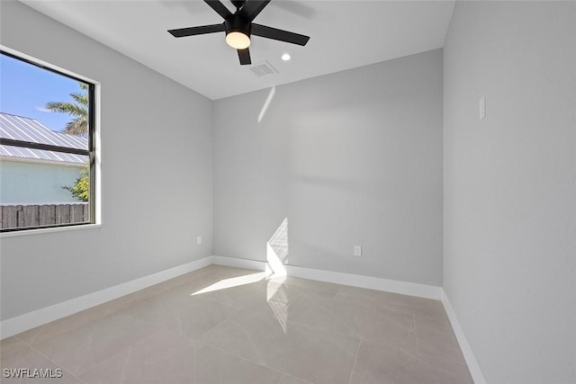 empty room featuring light tile patterned floors, visible vents, baseboards, and a ceiling fan